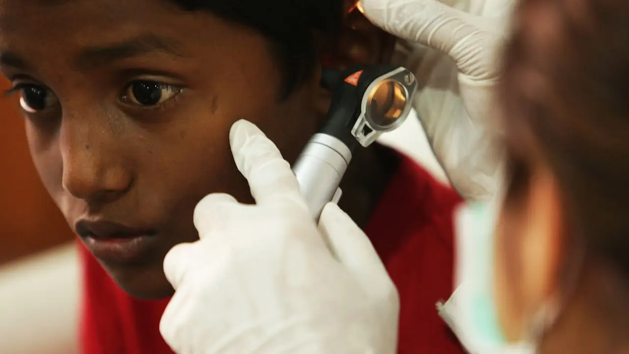 a boy having his ear checked with an otoscope