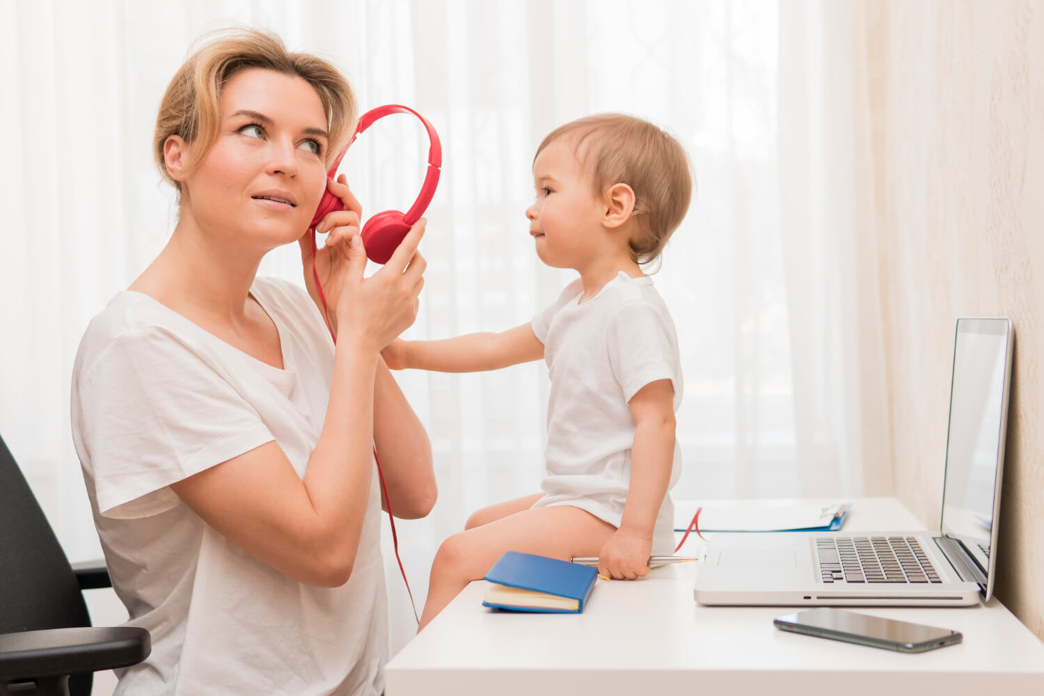 mother holding headphones and baby on desk