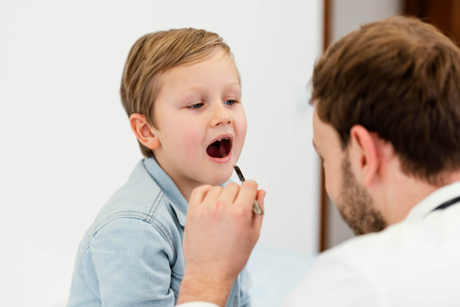 pediatrician checking pediatrician performing throat examination on a young boy